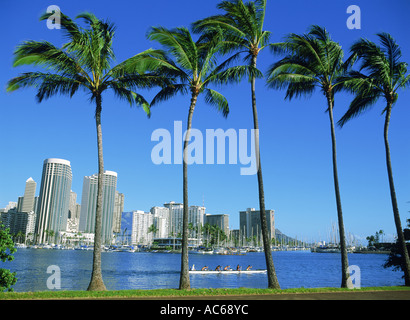 Auslegerkanu verlassen Ala Wai Hafen mit Diamond Head und Waikiki Hotels durch Palmen auf Magic Island Stockfoto