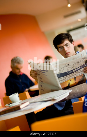 Mann liest Zeitung the Guardian in Aberystwyth Arts Centre Cafe Stockfoto