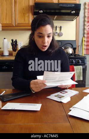 34-jährige Puerto Rican Amerikanerin, die Zahlung von Rechnungen in ihrer Küche Stockfoto