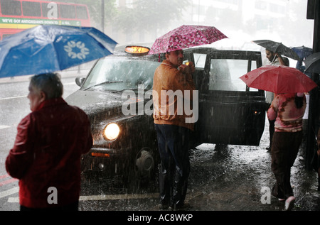 Menschen, gefangen in einem Regen Sturm auf Marylebone Road, London, vorbereiten, Int, ein Taxi zu bekommen. Stockfoto