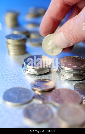 Person, die ein Pfund-Münze unter anderen britischen Münzen Studio gedreht Stockfoto