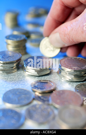 Person, die ein Pfund-Münze unter anderen britischen Münzen Studio gedreht Stockfoto