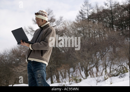 Junger Mann mit Computer außerhalb Stockfoto