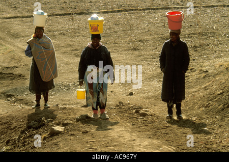 Drei Frauen balancieren Eimer mit Wasser auf ihren Köpfen Lesotho Stockfoto