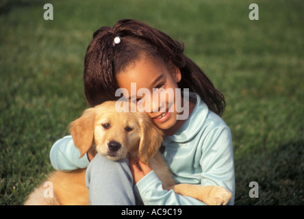 Eine junge ethnische multikulturellen rassisch gemischten Rassenmischung Mädchen 7-9 Jahre altes Kind spielen spielt Welpen golden Welpen POV Myrleen Pearson. ...... Ferguson Cate Stockfoto