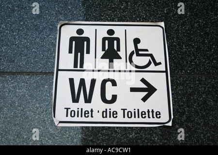 Universelle Schilder für Toiletten, die für Männer, Frauen und barrierefreie Toiletten bestimmt sind, mit mehrsprachigem Text für „Toilette“. Stockfoto