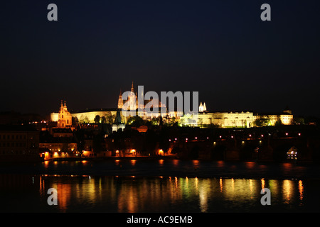 Die Prager Burg ist bei Nacht zu sehen, Moldau und Karlsbrücke sind im Vordergrund zu sehen. Stockfoto