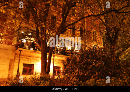 Restaurant im Freien auf einem charmanten Balkon eines historischen Gebäudes in Prag, beleuchtet bei Nacht, wo die Leute essen und das Ambiente genießen. Stockfoto