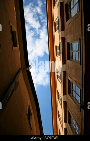 Blick auf den Himmel zwischen zwei schmalen Gebäuden in Prag, mit Architektur und blauem Himmel. Stockfoto