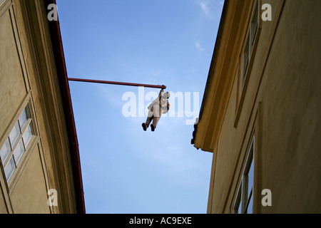 Sigmund Freud-Statue hängt mit einer Hand an einem Pfosten zwischen Gebäuden an einem klaren Himmel in Prag. Stockfoto