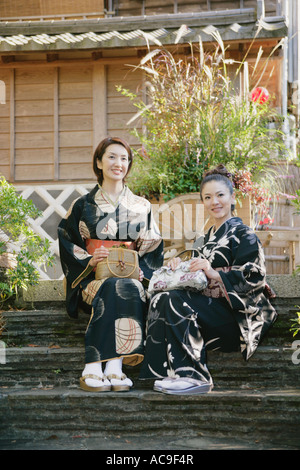 Zwei junge Frauen in Kimono sitzen auf Stufen Stockfoto