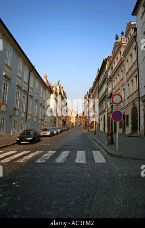 Nerudova Straße am frühen Morgen in Prag, gesäumt von historischen Gebäuden und Straßenlaternen, mit Autos, die entlang der Kopfsteinpflasterstraße geparkt werden. Stockfoto