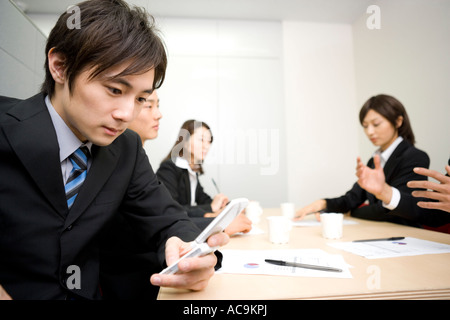 Junger Geschäftsmann mit Handy während der Sitzung Stockfoto