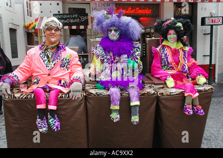 Drei Teilnehmer der Karneval im Hause gemachte Kostüme sitzen mit sehr kurzen Beinen als Parodie Akt Maastricht Niederlande Stockfoto