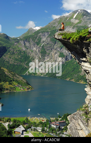 Frau sitzt auf einem Felsvorsprung, Hellesylt, Geiranger Fjord, mehr Og Romsdal, Norwegen Stockfoto