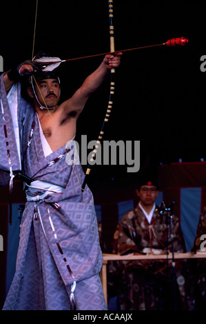 Ein japanischer Krieger Schauspieler schießen Pfeil und Bogen im Bogenschießen-Ritual-Bühnen-Performance und tragen Tracht aus Japan Stockfoto