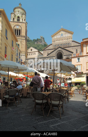 Amalfi historische, römisch-katholische Kathedrale, die von einer Bar im Freien, einem Café mit Sonnenschirmen versteckt ist, auf der geschäftigen Piazza del Duomo mit dem Glockenturm Salerno Campania Italien Stockfoto