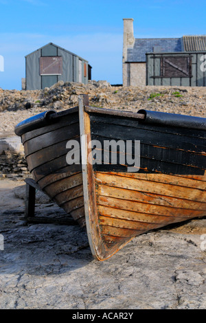 Kleine hölzerne Angelboot/Fischerboot auf dem Festland vor zwei alte Fischerhütten Stockfoto