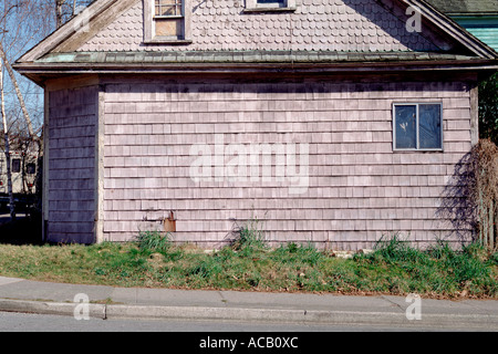 Verwittertes, unbemaltes Zedernhaus mit ungepflegtem Rasen und Bürgersteig Stockfoto