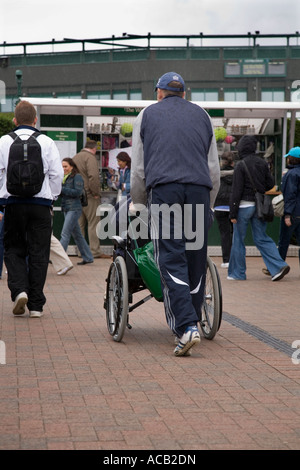 behinderte Personen im Rollstuhl geschoben in Wimbledon Tennis Championship UK Stockfoto