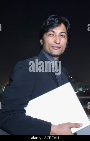 Porträt eines Geschäftsmannes hält einen laptop Stockfoto