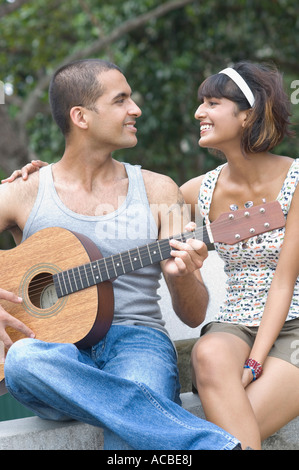 Nahaufnahme eines jungen Mannes, der eine Gitarre mit einer Mitte erwachsenen Frau neben ihm zu sitzen Stockfoto