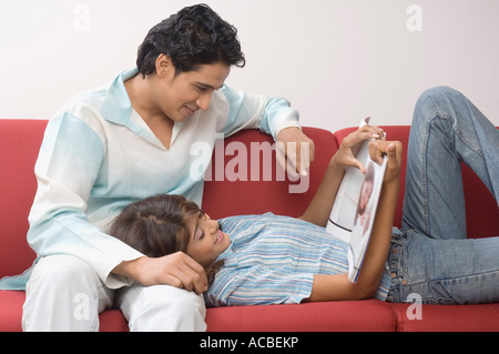 Seitenansicht eines jungen Paares auf eine Couch und ein Magazin zu betrachten Stockfoto