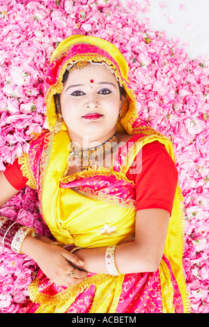 Porträt einer jungen Frau in ein Kostüm und liegend auf einem Bett aus Rosenblüten Stockfoto