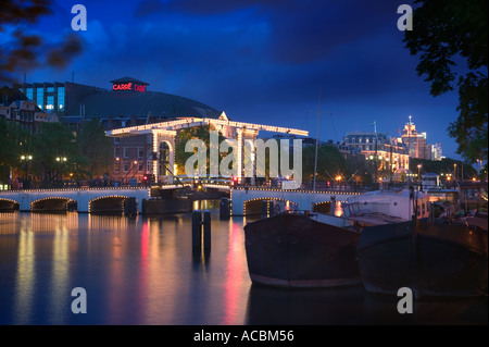 Magere Brug (Skinny Bridge) in Amsterdam in der Dämmerung mit dem Koninklijk Theater Carré hinter. Stockfoto