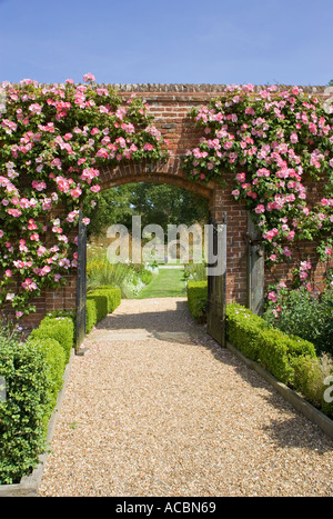 Weg durch Rose bedeckt Torbogen in ummauerten Garten UK Norfolk Stockfoto