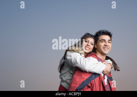 Seitenansicht einer jungen Frau Reiten Huckepack auf einem jungen Mann Stockfoto