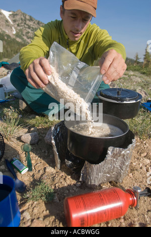 Gießen Haferflocken in einen Topf mit kochendem Wasser auf dem Campingplatz Wohnmobil Stockfoto