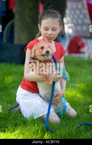 Ein kleines Mädchen hält eine Parade einen Hund, der Farben rot, weiß und blau für den 4. Juli gezeichnet wird Stockfoto