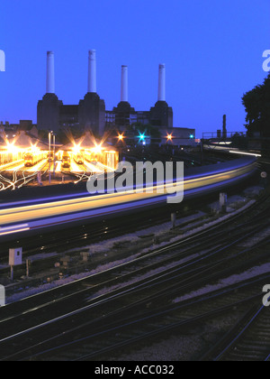 Zug von Victoria Station vorbei jetzt stillgelegten Battersea Power Station in London England UK Dämmerung Nacht Stockfoto