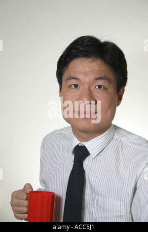 junger Mann von chinesischer Abstammung, die mit einem roten Coffeee Becher Stockfoto