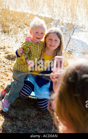 Mädchen fotografieren ihre Geschwister mit ihrem Mobiltelefon. Stockfoto