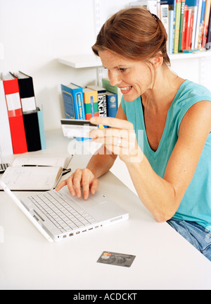 Eine Frau mit einer Kreditkarte an einem Notebook arbeitet. Stockfoto
