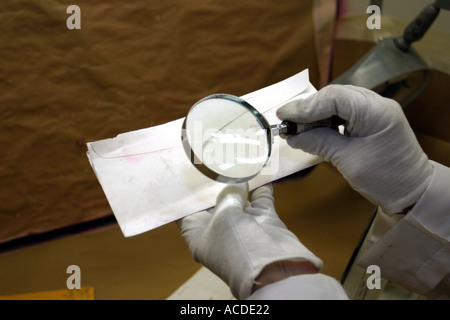 Fingerabdruck-Experte Studium druckt auf Umschlag mit Lupe. Nebraska Crime Lab, USA. Stockfoto