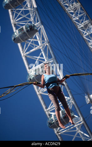 Junge Frau Bungee springen auf einem Trampolin vor dem London Eye, South Bank, London, England, Großbritannien Stockfoto