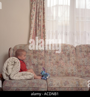 Ein kleiner Junge schaut TV sitzen auf dem Sofa, Bristol, UK. Stockfoto