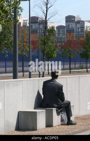 Ein Mann sitzen essen Mittagessen mit Blick auf Hochhäuser auf der Halbinsel Greenwich, London, UK. 2005. Stockfoto