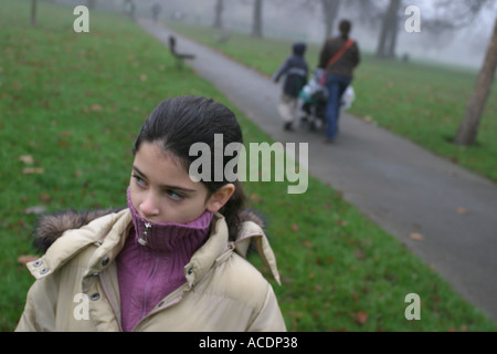 Ein 9 Jahre altes Mädchen auf dem Weg zur Schule mit ihrer Mutter und Geschwister im Hintergrund, Clissold Park, Stoke Newington, London. Stockfoto