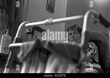 Eine ältere Frau sitzt mit ihrer Gehhilfe. Stockfoto