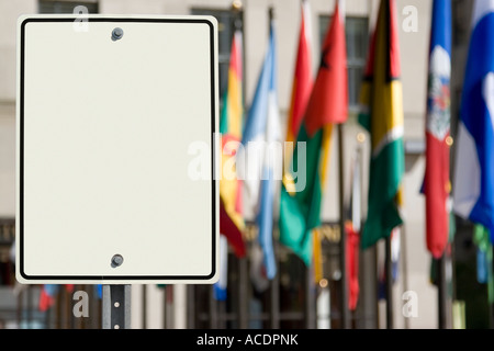 Leeres weißes Schild vor einer Gruppe von internationalen Flaggen. Stockfoto