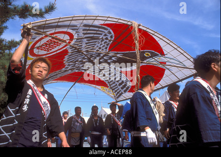 Männer, die Happi tragen, tragen einen großen Bambus- und Papierdrachen über den Drachenplatz während des Takoage Gassen Festivals in Hamamatsu, Japan. Stockfoto
