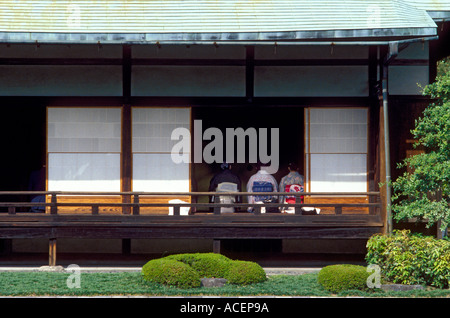 Frauen tragen Kimono sitzen in traditionelles Gebäude mit offenen Schiebetüren der Shoji-Panel in Garten Stockfoto