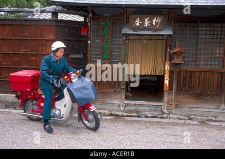 Japanische Postmitarbeiter, die auf einem roten Motorroller Post liefern, sind überall in Japan zu sehen. Stockfoto