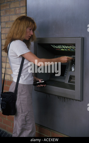 Frau immer Geld aus einem Loch in der Wand Stockfoto