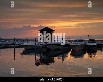 Luxus-Sport-Yachten im Hafen bei Sonnenuntergang mit orange Wolken Peschiera del Garda Italien Stockfoto