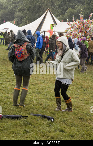 Mädchen tanzen im Regen in den grünen Feldern auf dem Glastonbury Festival 2007, Somerset, England. Stockfoto